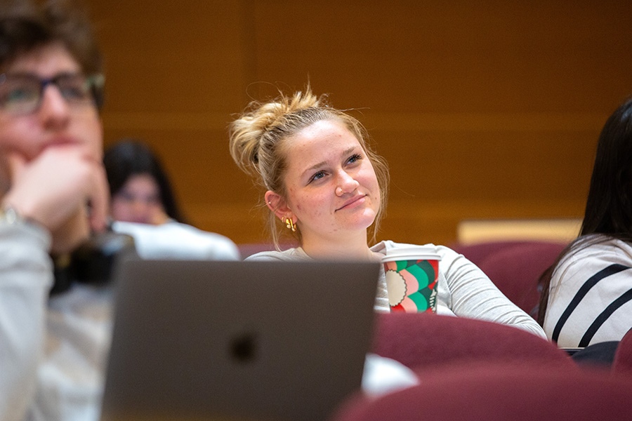 A student smiles while listening to a lecture.