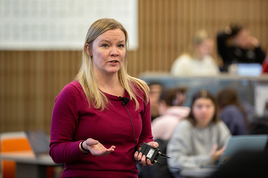 Sara Stifano, assistant professor-in-residence of communication, speaks in front of a class while wearing a microphone.
